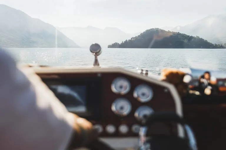 Blick auf die Berge des Comer Sees durch das Fenster einer Yacht. Silhouetten von Hügeln am Horizont. Luxus-Urlaub und Kreuzfahrt-Konzept. Bootsfahrt. Yachting in Italien.