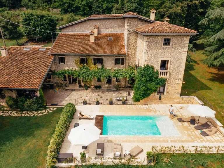 Luftaufnahme eines Paares beim Entspannen am Swimmingpool in der Nähe einer Villa in Italien