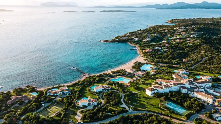 villas and hotels in paradise on the island of sardinia italy. right on the bay and with a charming white beach. perfect for swimming, diving. warm light shines, clear water. drone aerial view.